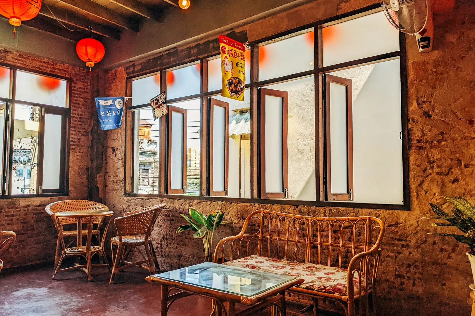 A café with tall wooden windows, rattan chairs and paper lanterns